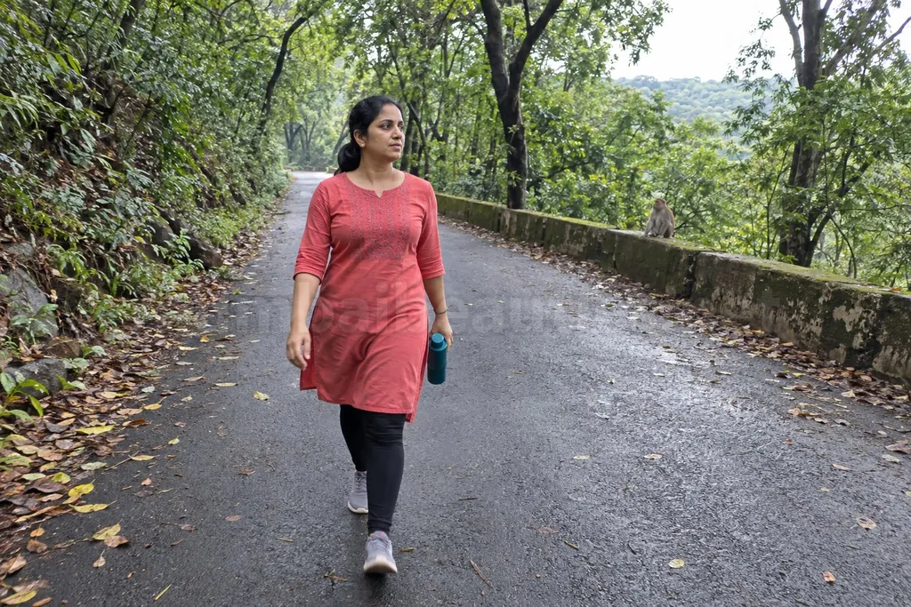 Woman walking on a tree-lined road inside Sanjay Gandhi National Park in the morning, Borivali call girls
